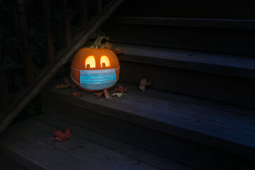 Lighted Carved Jack-o-Lantern dressed up for Halloween with COVID Pandemic face mask - wide angle horizontal