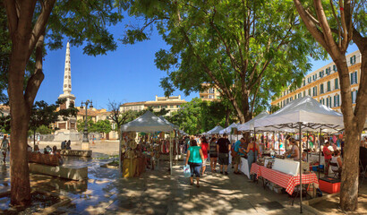 Malaga, Spain: summer market at Plaza de la Merced in the old town, on a cloudless day, with rows of market stalls and many visitors.