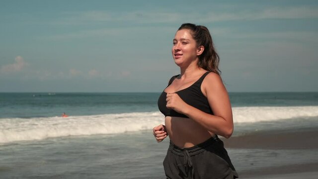 plus-sized woman is jogging alone on sea beach