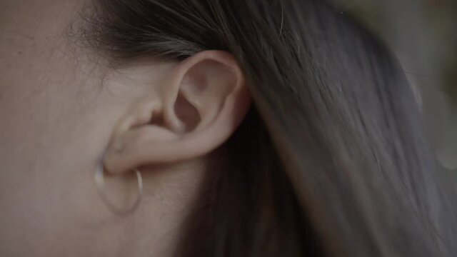 Primer plano de la oreja de mujer con pendiente escuchando sonido en la naturaleza HD