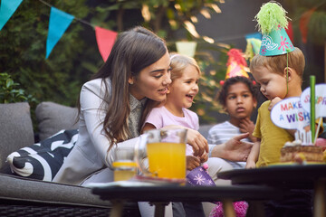  beautiful female playing with group of children at birthday party