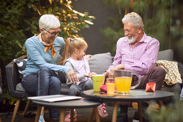 grandparents enjoying with their granddaughter in the backyard