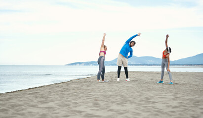 Friends doing fitness with the music on the beach