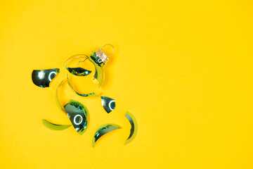 broken Christmas tree ornament ball on yellow background. broken old xmas decorations