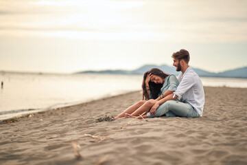 Young lovers sitting in a hug on the beach