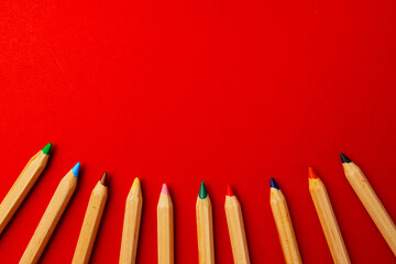 Row of color wooden pencils on red background