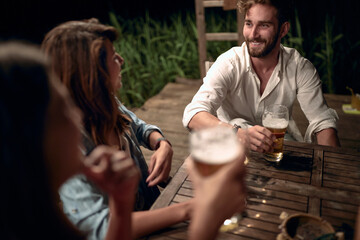 Fototapeta premium A man in girls company in the bar on the lake