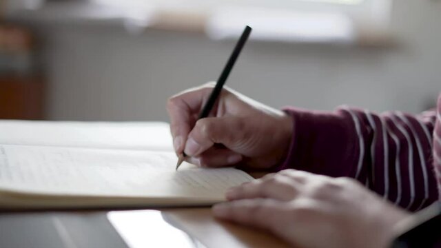 Woman taking notes from her ipad to a paper notebook with a pencil