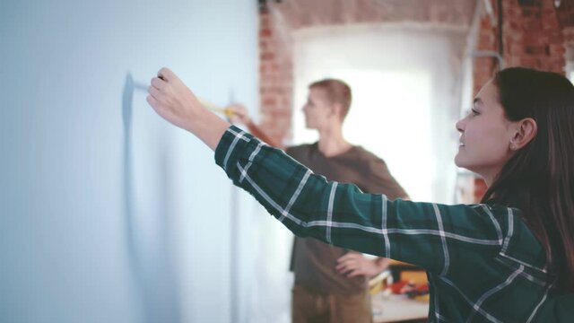 Young couple measure wall with measuring tape doing apartment repair together