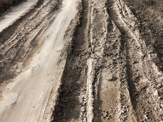 Tyre track and human footprint on sand texture background. Traces of off-road tires. Cracked earth on country road with traces of tires, cars, cracks and dirt. To use as background