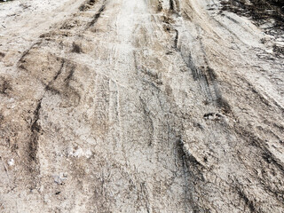 Tyre track and human footprint on sand texture background. Traces of off-road tires. Cracked earth on country road with traces of tires, cars, cracks and dirt. To use as background