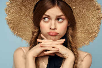 Girl in a straw hat portrait close-up pigtails fun red hair blue background