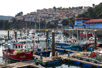 Spain; Sep 2020: Traditional village by the Atlantic sea. Colorful fishing boats on the harbor. White houses built on the hill with red roofs behind. Camino de Santiago. Lastres, Austurias, Spain