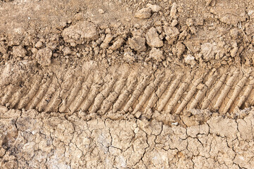 Tyre track and human footprint on sand texture background. Traces of off-road tires. Cracked earth on country road with traces of tires, cars, cracks and dirt. To use as background