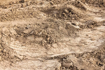 Tyre track and human footprint on sand texture background. Traces of off-road tires. Cracked earth on country road with traces of tires, cars, cracks and dirt. To use as background