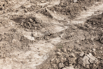 Tyre track and human footprint on sand texture background. Traces of off-road tires. Cracked earth on country road with traces of tires, cars, cracks and dirt. To use as background