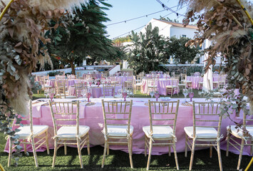 pink decoration for an event or wedding with tables and chairs in a green and natural place 