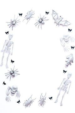 Halloween frame with painted silver bats, skeletons, spiders and black cat confetti on white background, copy space, vertical image
