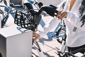 Foreground of female hands using a card bicycle rental service. Ecological transport concept.