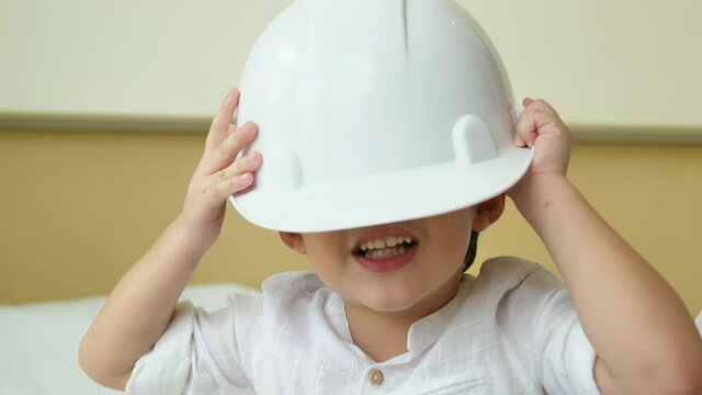 Dreaming about future. Boy in white safety helmet very happy and funny at home. 