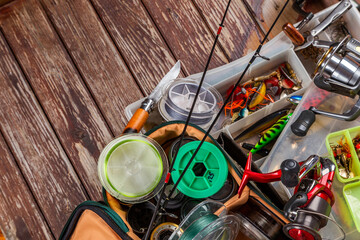 Different fishing tacles with rod and reels on wooden brown background.