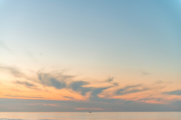 Fishing boat on the horizon on a ry sunset with some clouds on the beach of Ameland in the Netherland, idillic beautiful colors nature photo
