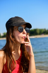 Young woman smoking cigarette on the beach 