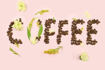 Word coffee from beans with flowers on pink background. Concept International Coffee Day, cappuccino