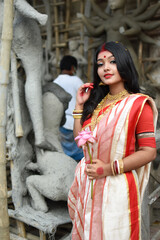 Portrait of stunning Indian woman draped in traditional saree adorned with gold jewellery, posing...