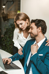 Girl in the office hugs a sitting colleague. Seducing a subordinate in the office concept. High...