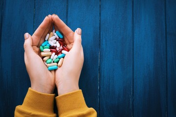 Woman hand holding different  pills on the wooden background.
Full palms of pills. Medicine concept. - 378774807