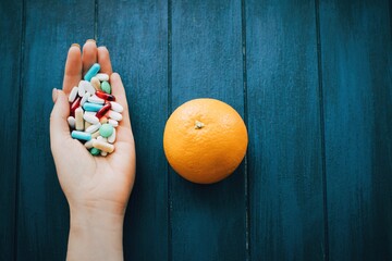 Woman hand holding different  pills on the wooden background.
Full palms of pills. Medicine concept. - 378774839