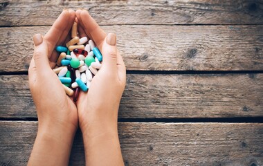 Woman hand holding different  pills on the wooden background.Full palms of pills. Medicine concept. - 378774872
