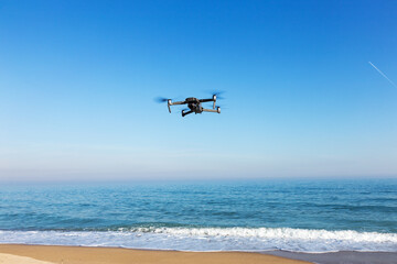 Fototapeta na wymiar Drone with camera flies over the sea against a blue cloudless sky