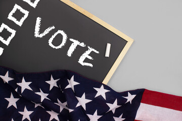 Presidential Elections in United States of America. Blackboard, chalkboard with vote word and american flag flat lay on gray background top view. Voting concept. Stock photo.