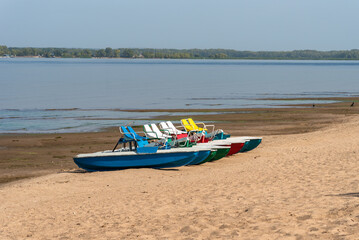 Naklejka premium Pedalo rowing catamara stand on an empty sandy beach - pandemic, no people