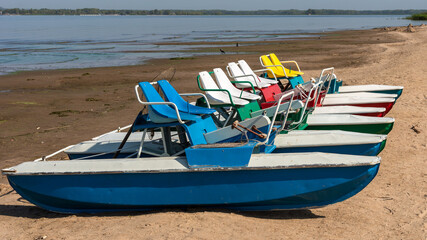 Pedalo rowing catamara stand on an empty sandy beach - pandemic, no people