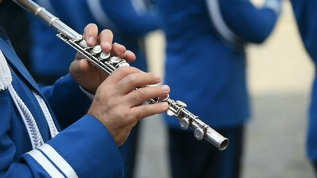 Military orchestra man performing during ceremony. Detail with musician playing on flute.