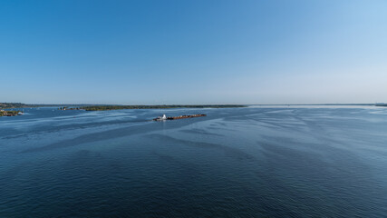 Fototapeta na wymiar A large barge with sand sails along the coast along the wide Volga river