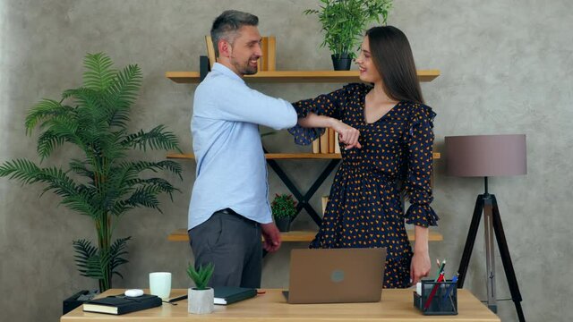 Smiling woman and man greet elbows employees work together in office preparing presentation for meeting help to solve problem. Female manager showing progress report to businessman on laptop computer