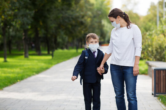 Mom And Her Son Schoolboy Wearing Mask With Backpack Going To School. Copy Space