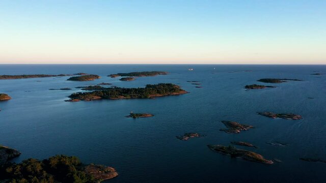 Aerial view of small islands, towards a fishing ship, on the open sea of the Baltic sea, during sunset, in the archipelago of Sweden - tracking, drone shot