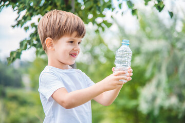 cool baby drinks clean water from a bottle on a sunny day in nature
