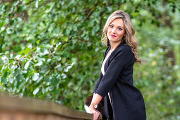young blonde woman standing near wooden railings in park