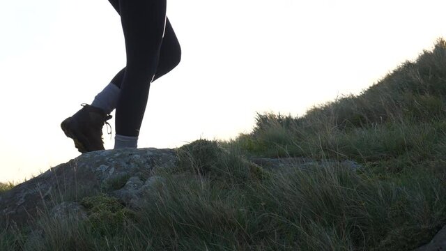 Close woman hiking up a mountain at sunrise. Active healthy lifestyle concept, positivity and leisure