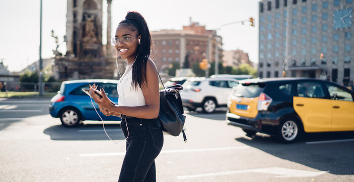 Cheerful African American woman using tablet and earphones - Powered by Adobe