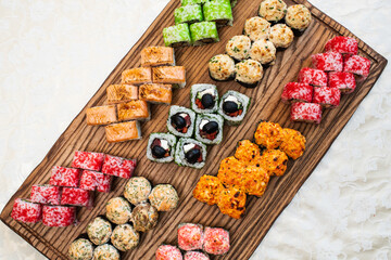 Different types of delicious and juicy sushi and rolls on a wooden board