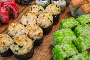 Different types of delicious and juicy sushi and rolls on a wooden board