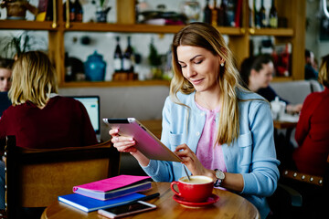Positive woman browsing tablet in cafe