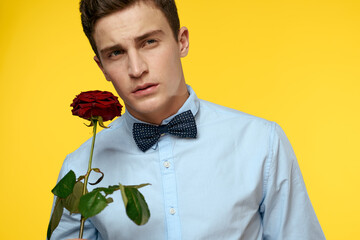 Portrait of a man with a red rose on a yellow background and a light shirt bow tie gentleman